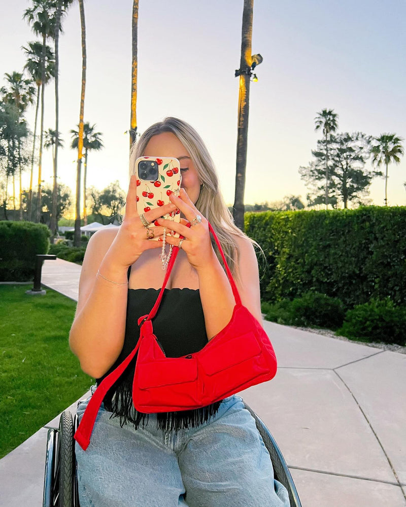 Woman in red top taking photo with colorful patterned phone case outdoors