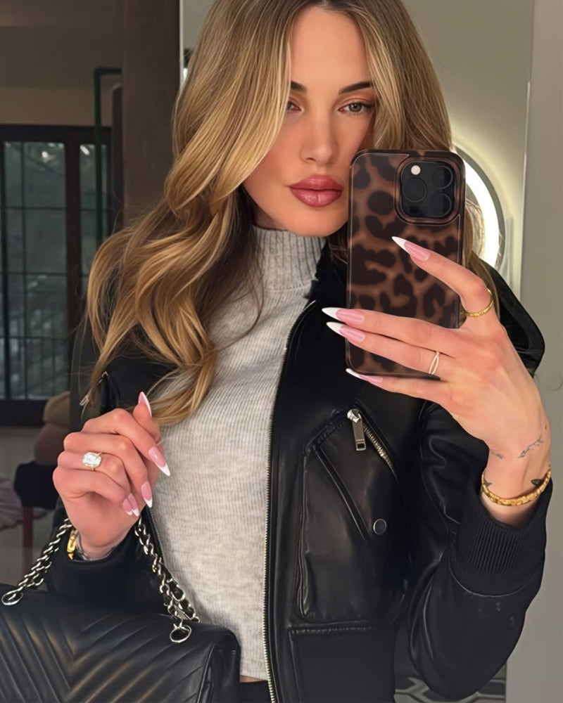 Blonde woman taking mirror selfie with leopard print phone case in black leather jacket